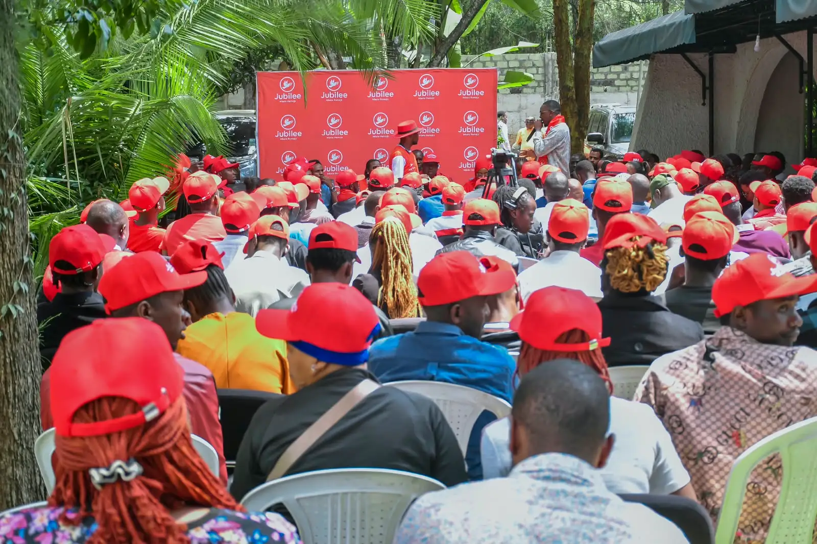 Seated audience in red caps at a youth forum